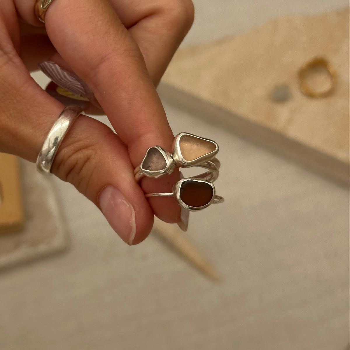 Hand wearing multiple rings with a neutral background