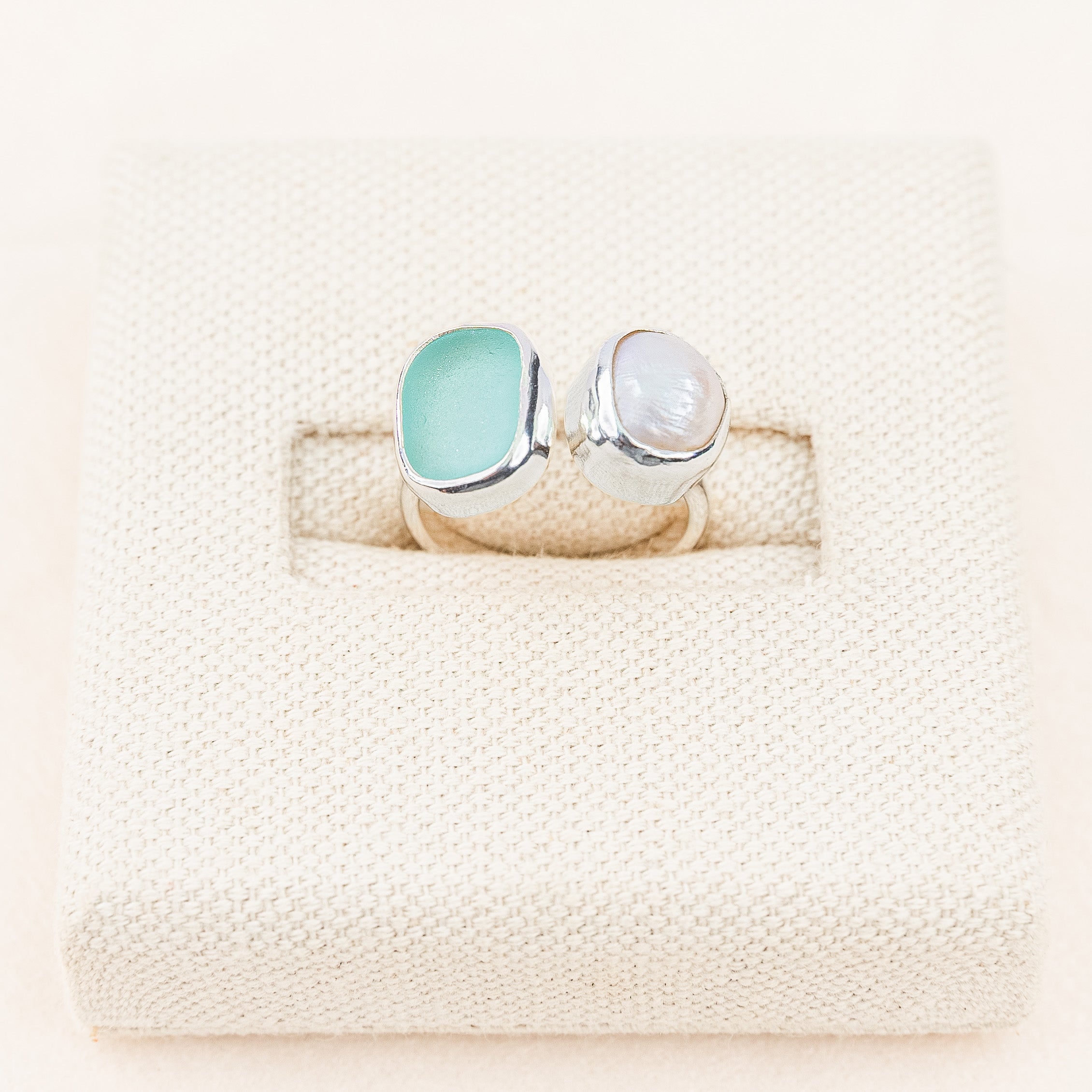 Two rings with gemstones on a textured beige surface