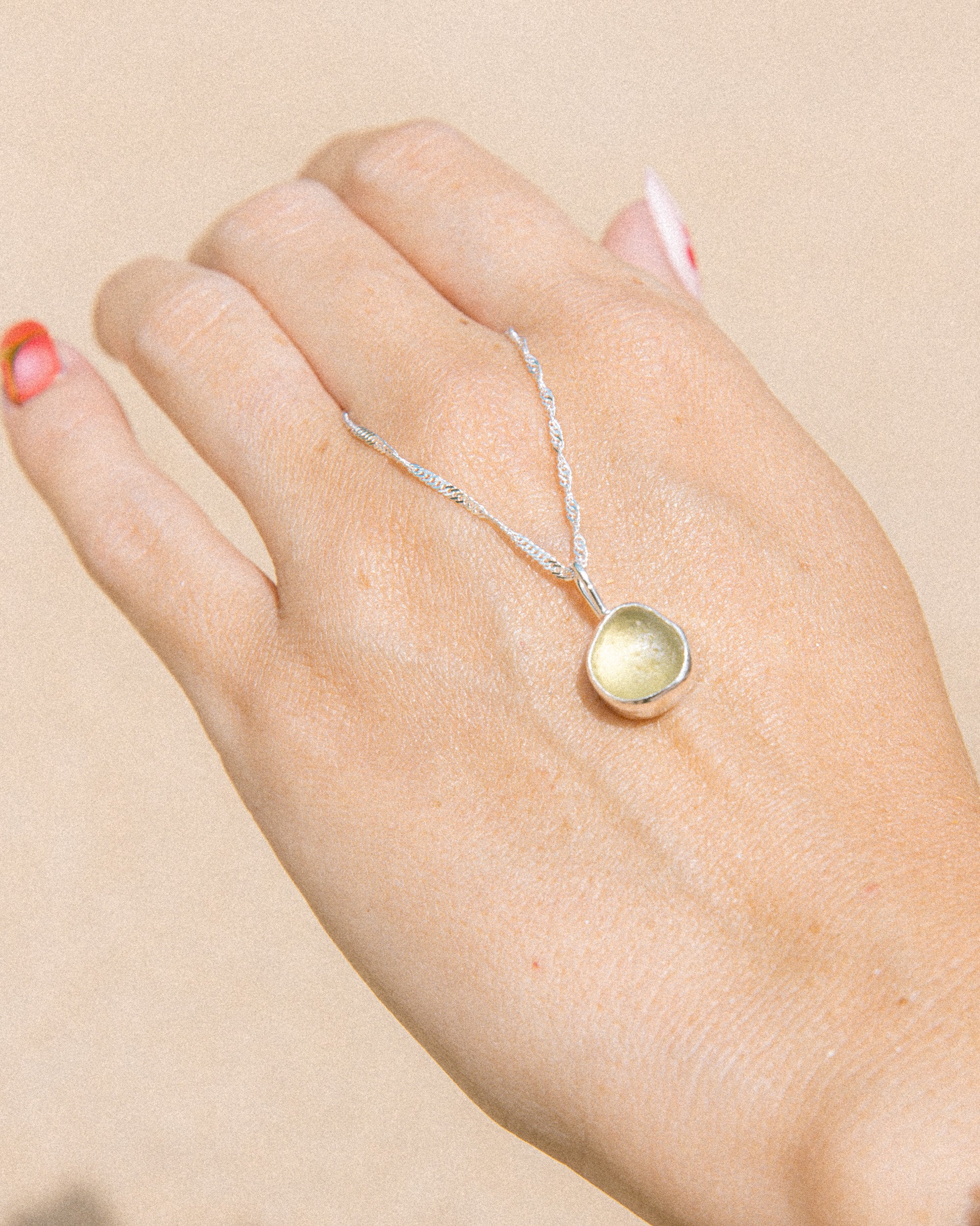 Citron sea glass necklace held in hand, handmade sterling silver, Broken Wave Jewellery Newquay
