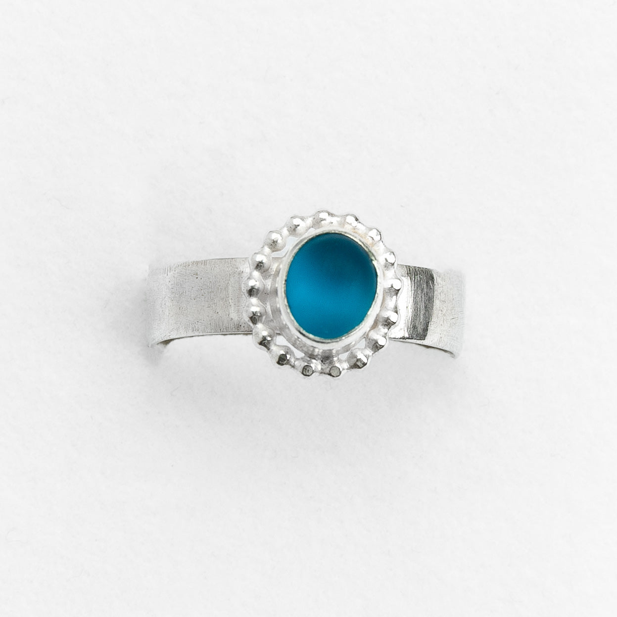 Silver ring with a blue stone on a white background