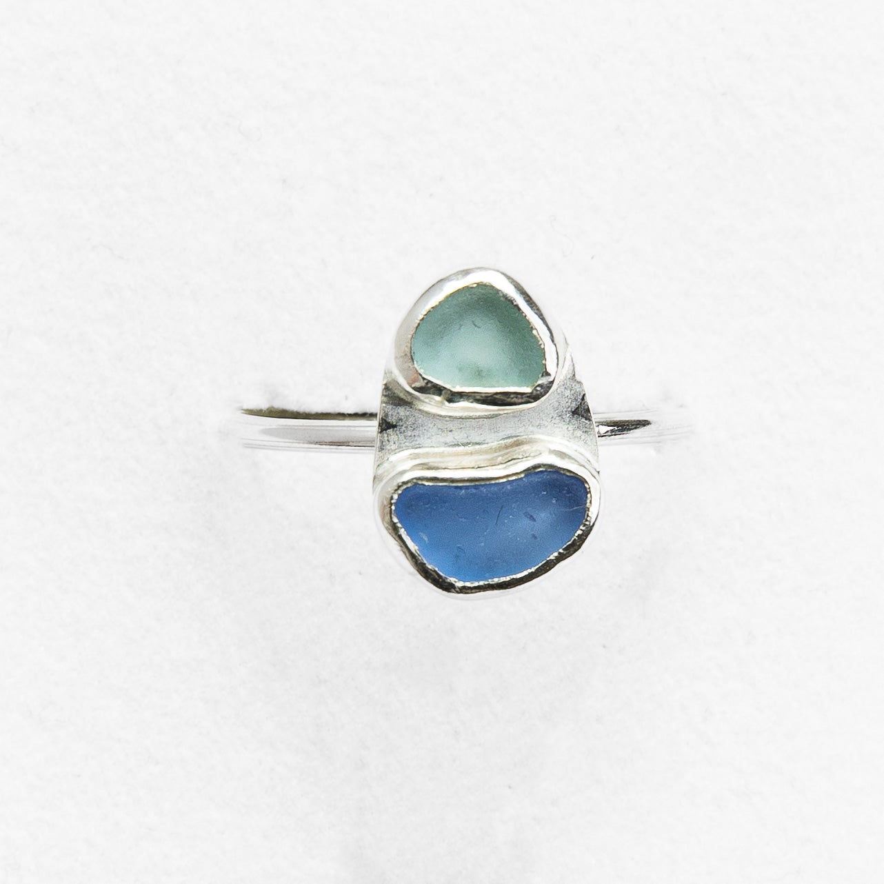 Silver ring with two heart-shaped blue stones on a white background
