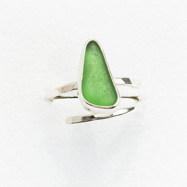 Green sea glass ring with silver band on a white background