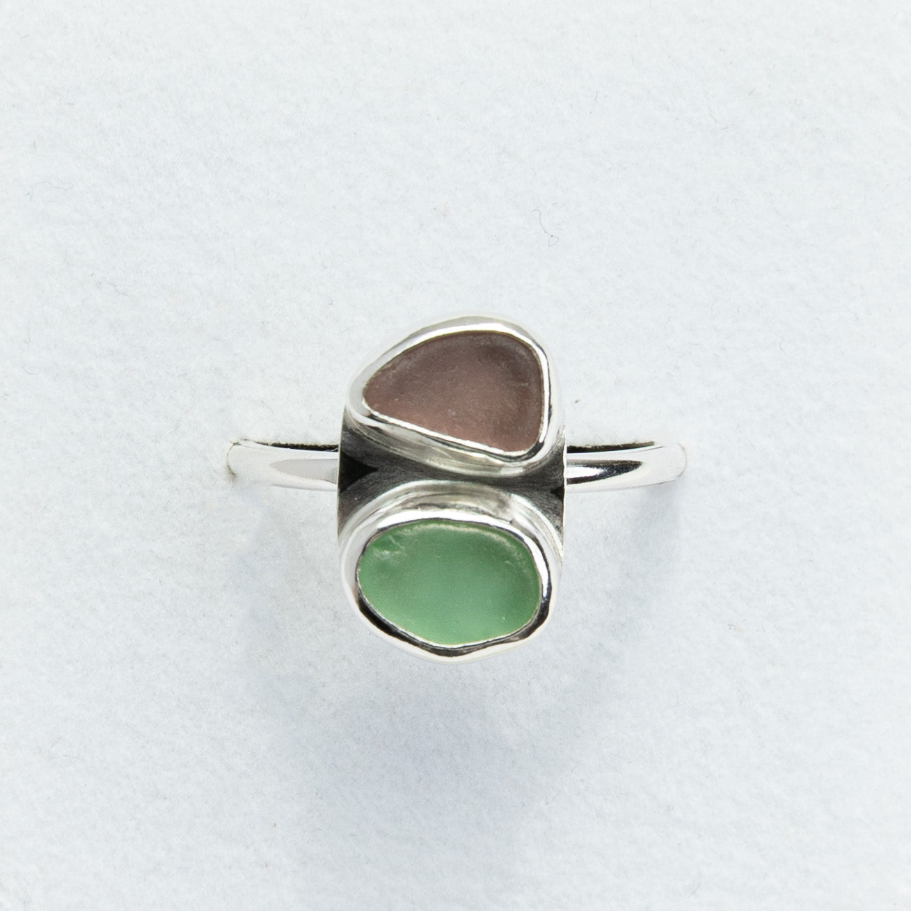 Silver ring with two colored stones on a light gray background