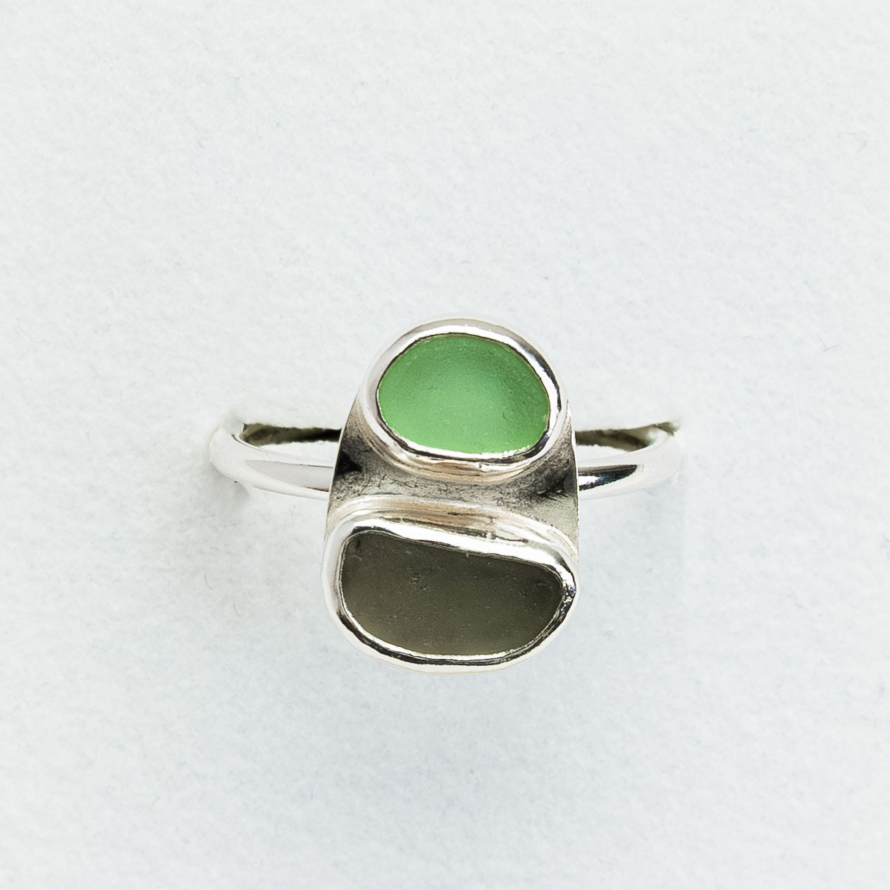 Silver ring with green stone on a white background