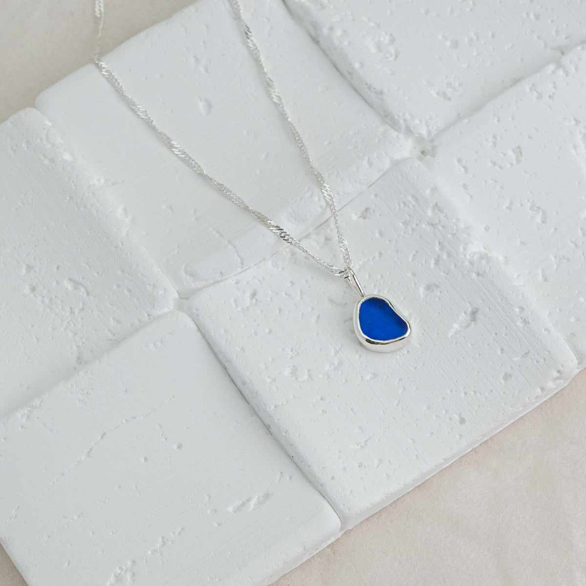 Necklace with a blue pendant on a textured white surface