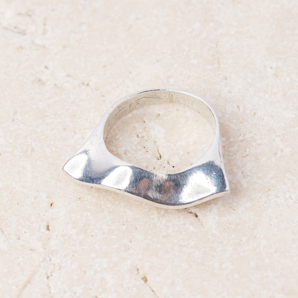 Side view of the silver wave ring showing its curved, flowing shape