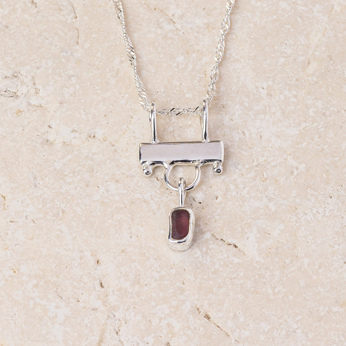 Deep purple sea glass hanging from a sterling silver bar on a fine chain, handmade in Cornwall