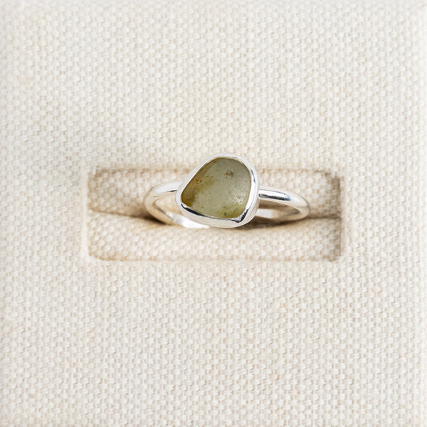 Olive green sea glass ring in sterling silver on textured white surface, Broken Wave Jewellery Cornwall
