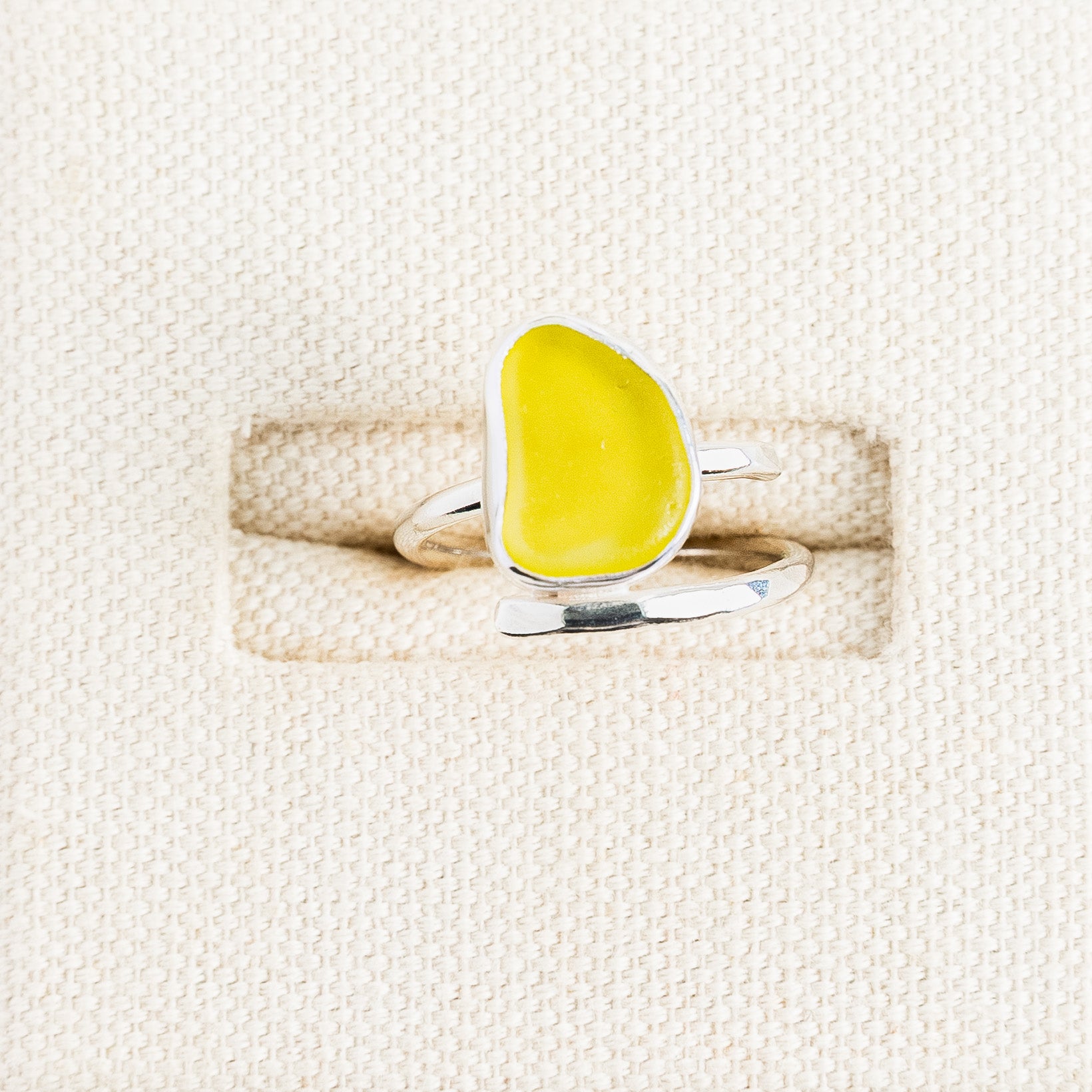 Bright yellow sea glass ring in sterling silver on textured white surface, Broken Wave Jewellery Cornwall
