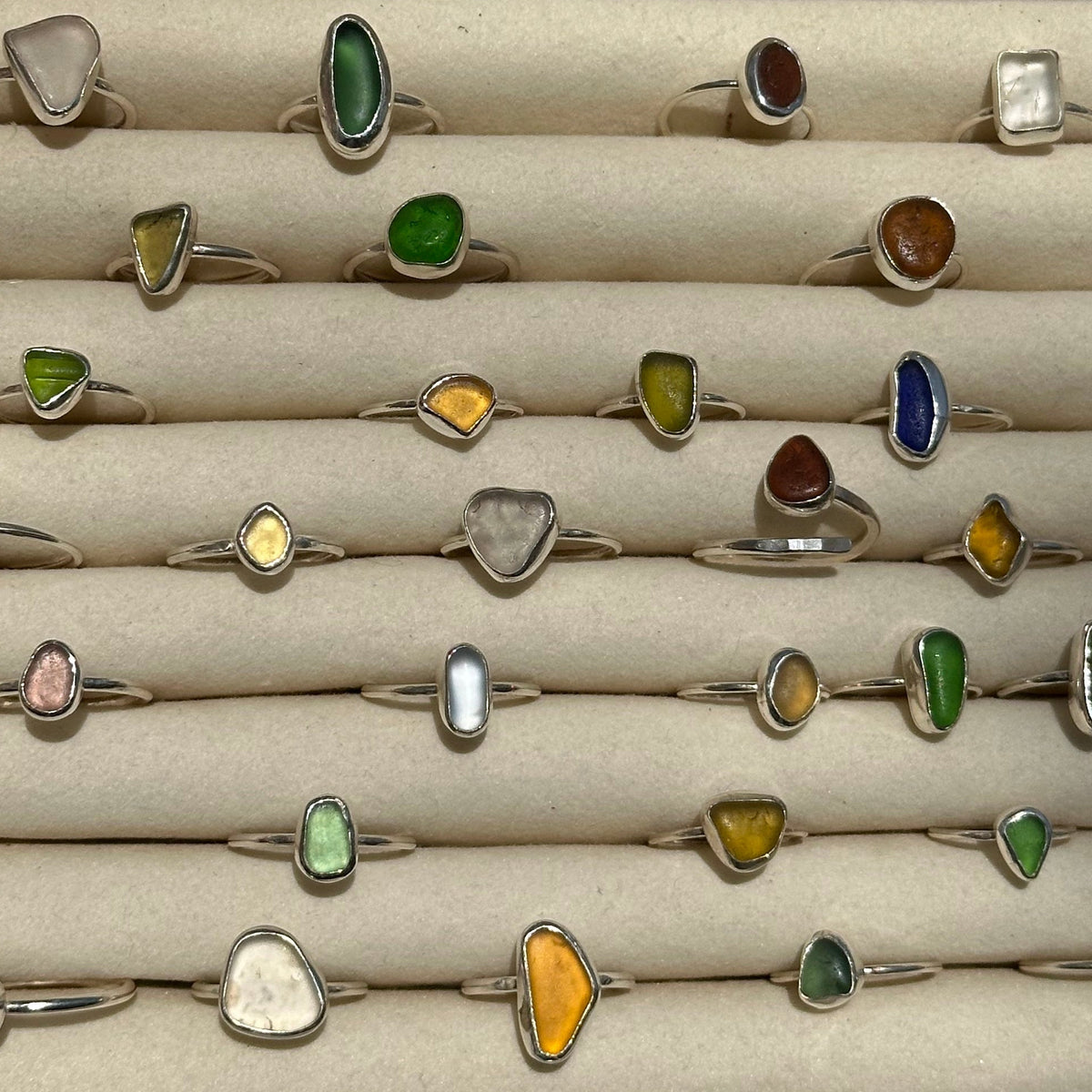 Collection of various rings with colored stones in a display case.