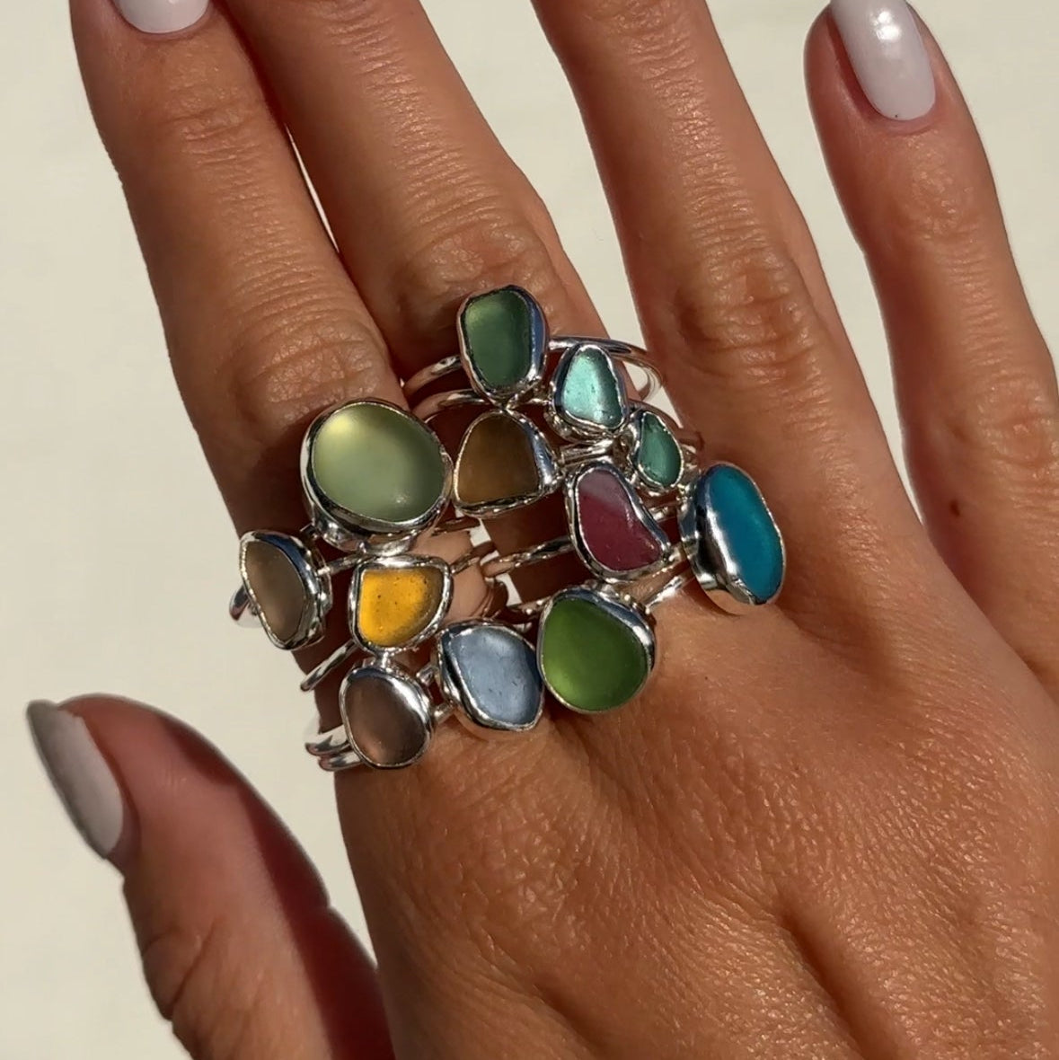 Hand wearing a colorful ring with a neutral background