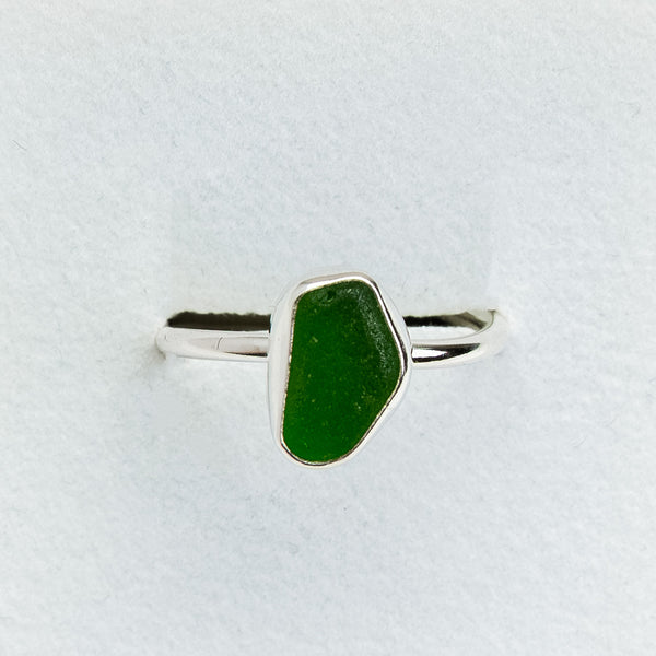 Green ring with silver band on a light gray background